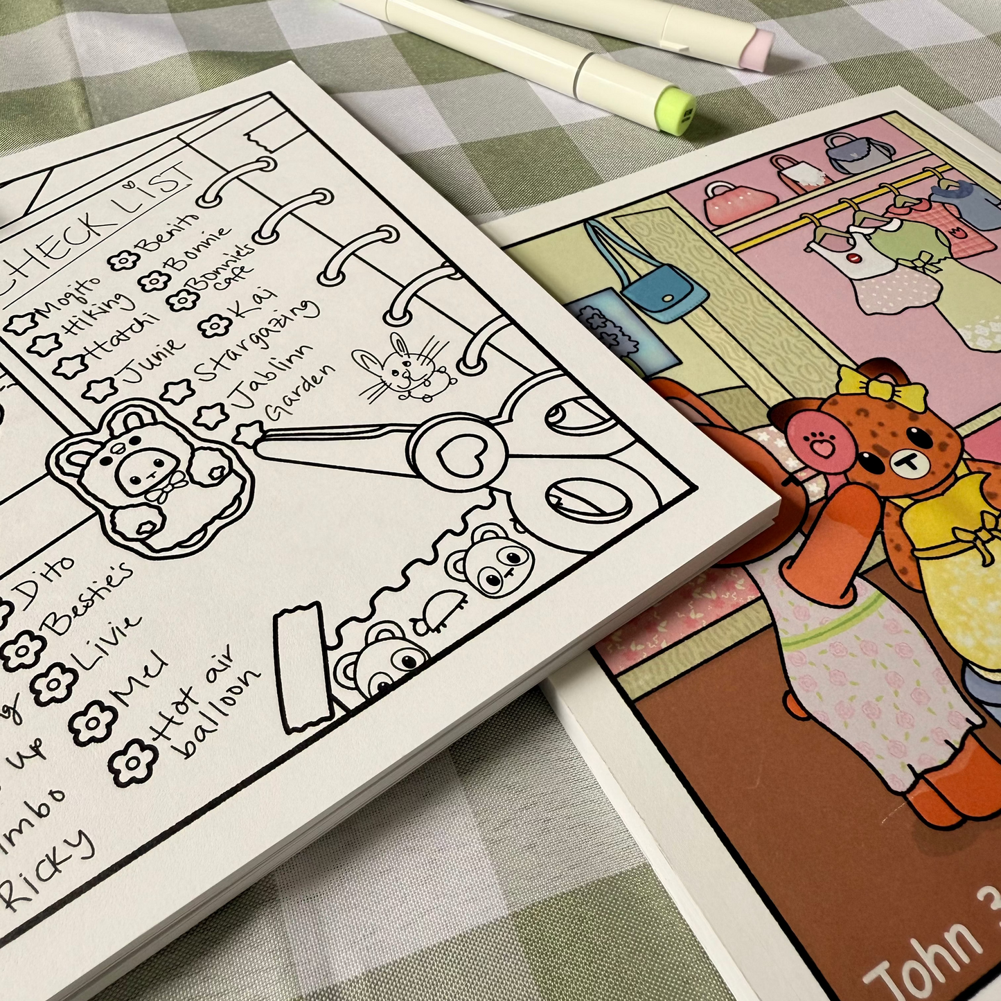 Two coloring books on a checkered tablecloth with markers.