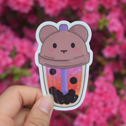 gradient boba drink with pink yellow orange. bear lid and a purple straw