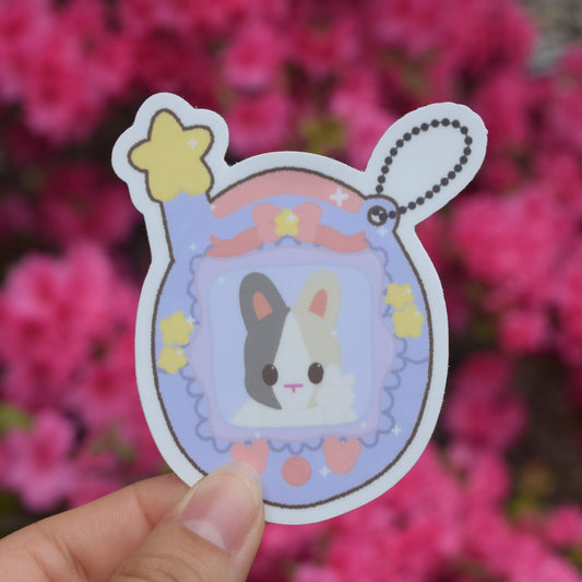 purple tamagotchi with bunny in the center. little accents of pink and yellow shapes