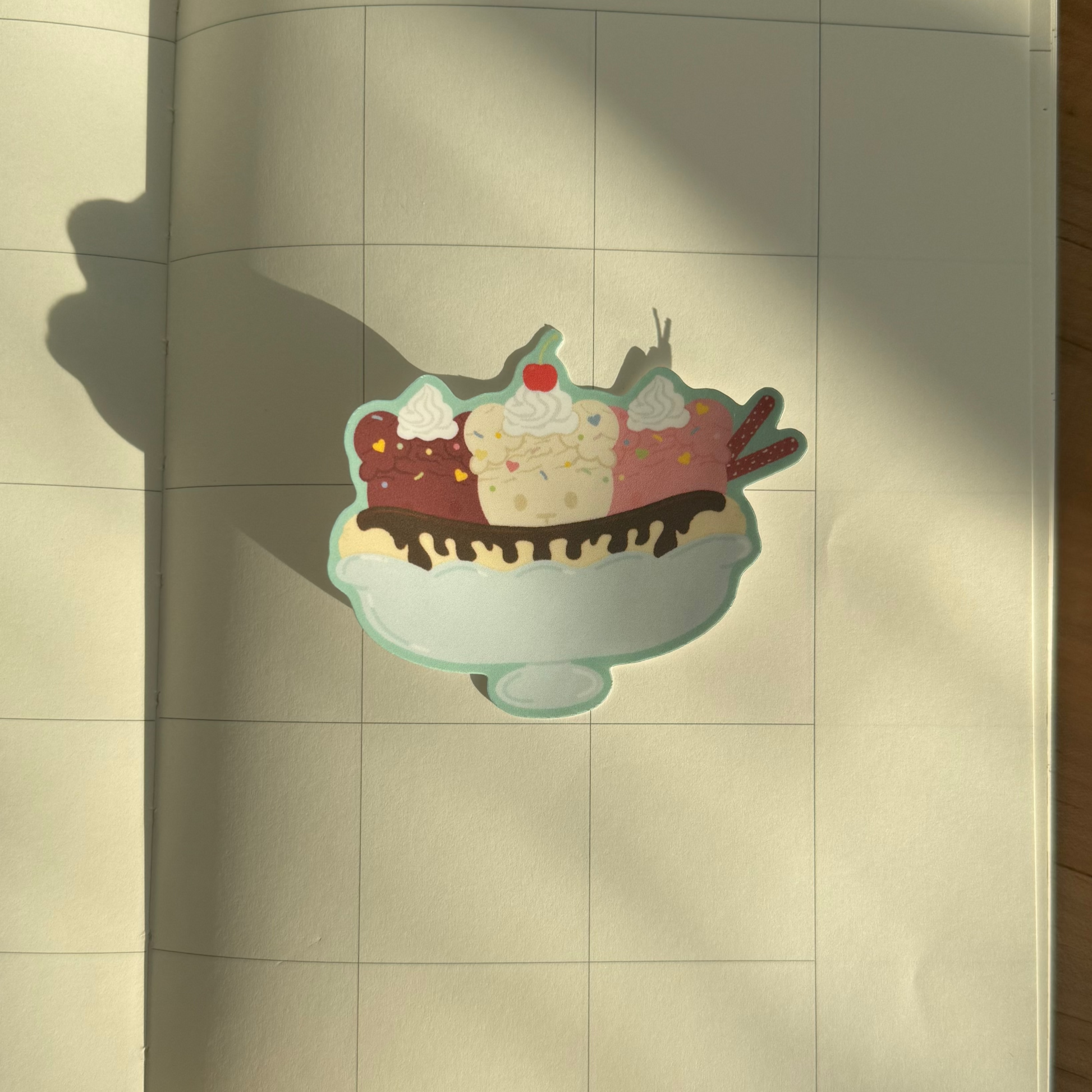 Open notebook with a sticker of a bear banana split on a wooden surface